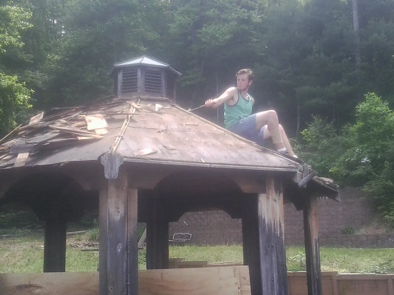 Tearing the old roof off a wooden gazebo before new shakes in Newington