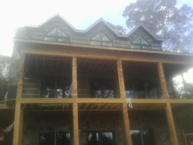 Dormers and porch framing on a large log home under construction — Roof Coating work by our crew in Newington