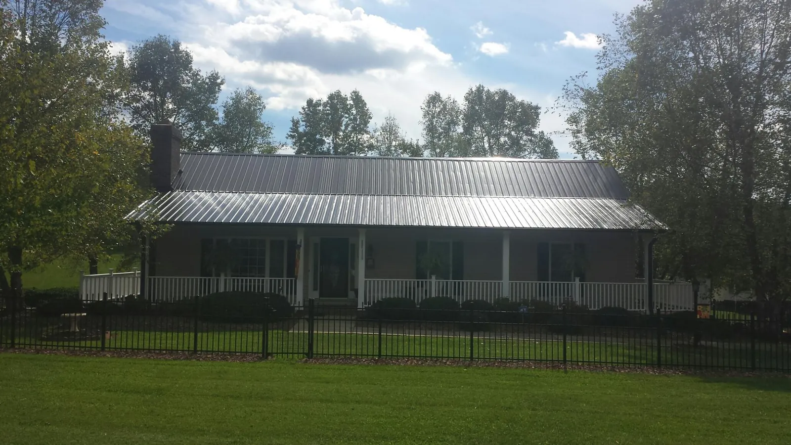 Gray metal roof on a brick ranch with a full width front porch — Gutter Guard Installation work by our crew in Newington