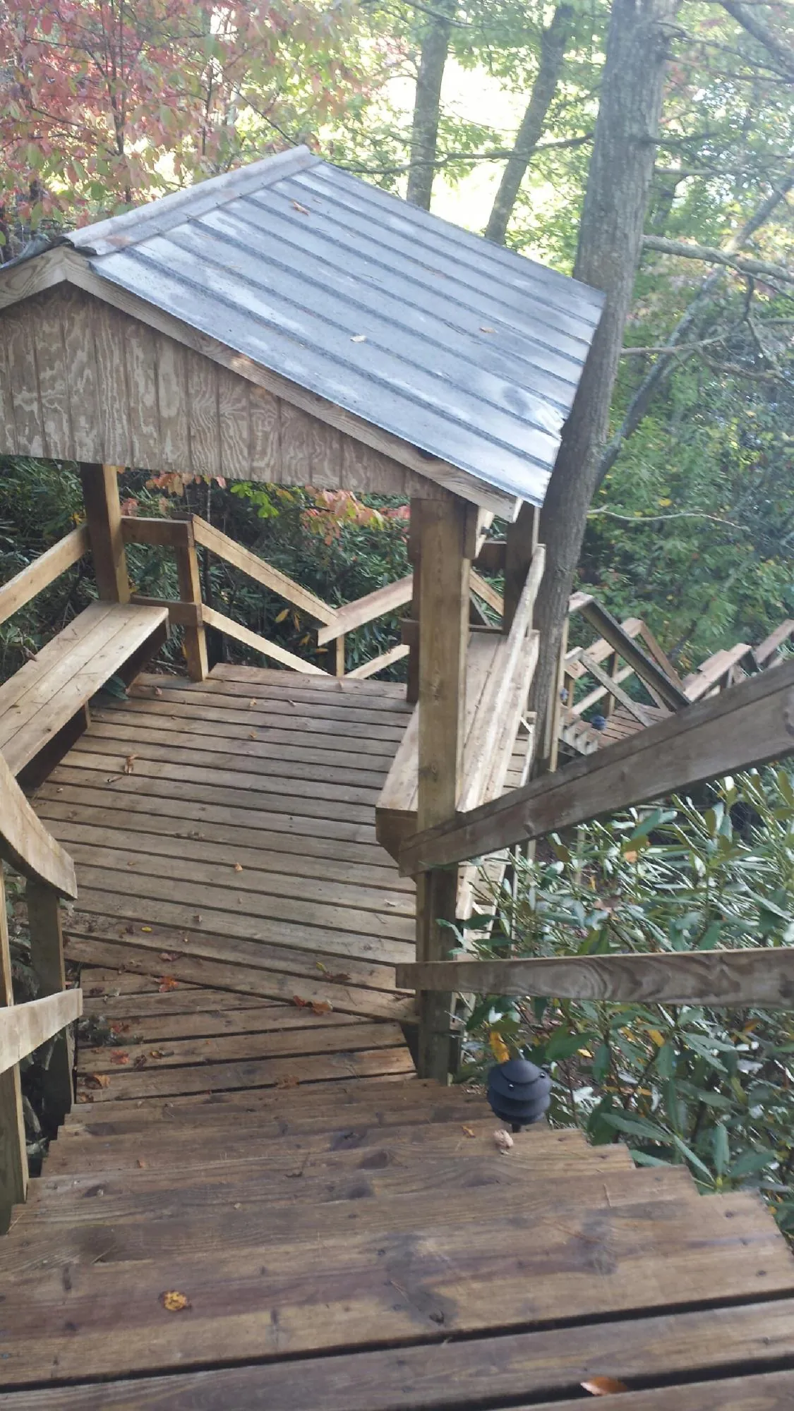 Metal roofed shelter over wooden steps on a wooded walkway — Skylight Repair & Installation work by our crew in Newington